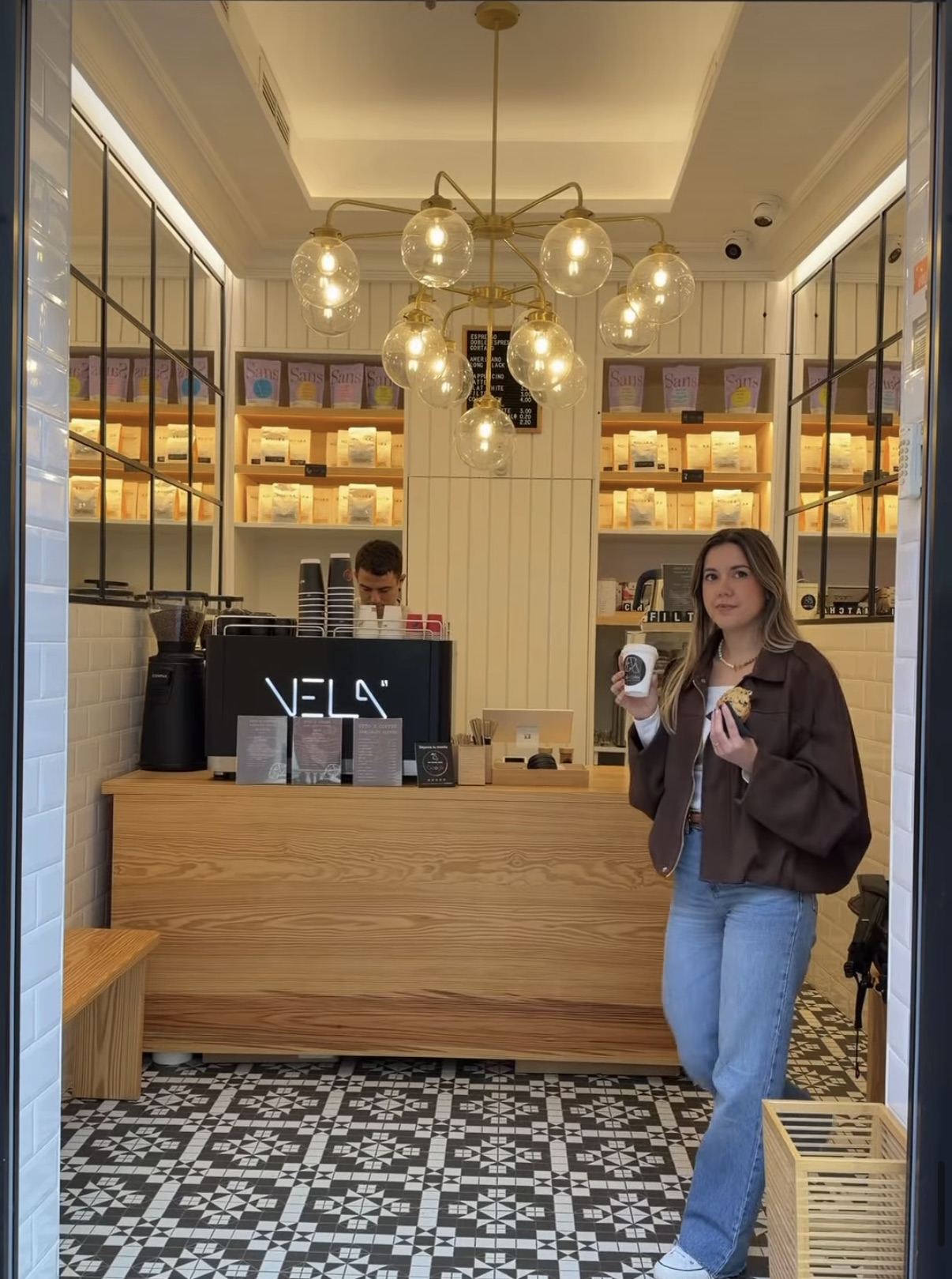 Interior de Otto's Coffee: barra de madera, lámparas de globo doradas y estanterías con café